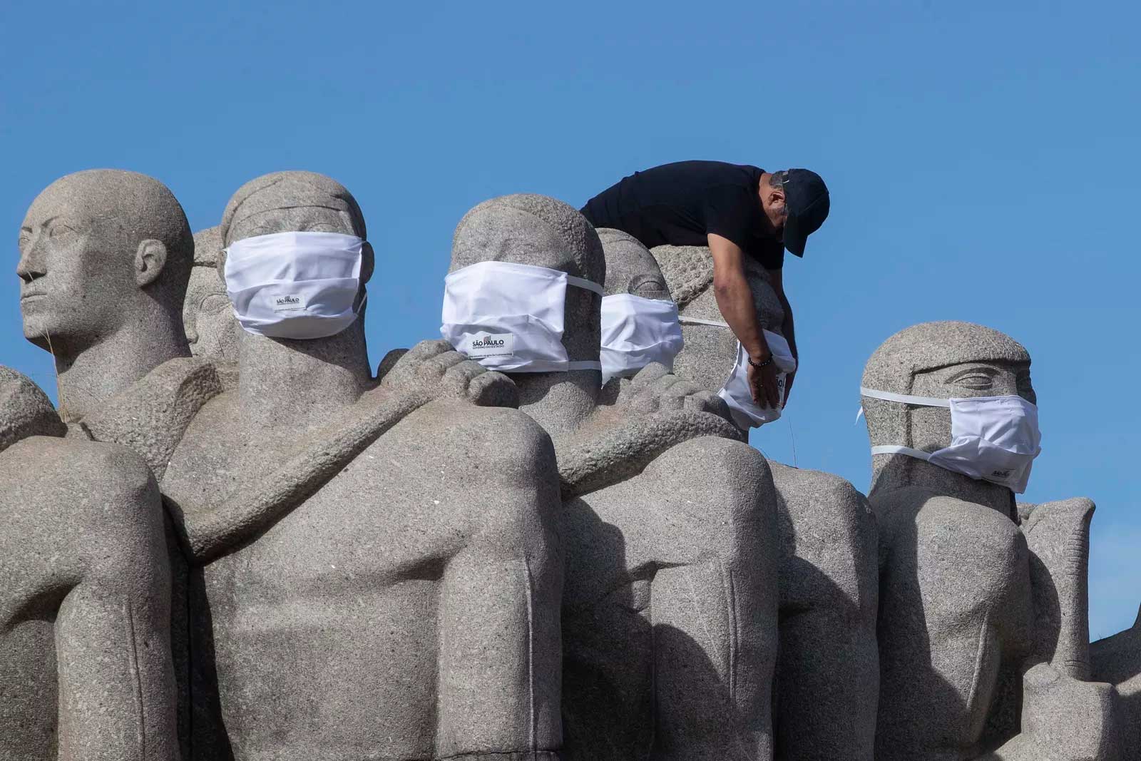 
 12 de maio - Trabalhador coloca máscaras no 'Monumento às bandeiras' para promover o uso de máscaras em meio à pandemia de coronavírus, em São Paulo — Foto: Andre Penner/AP